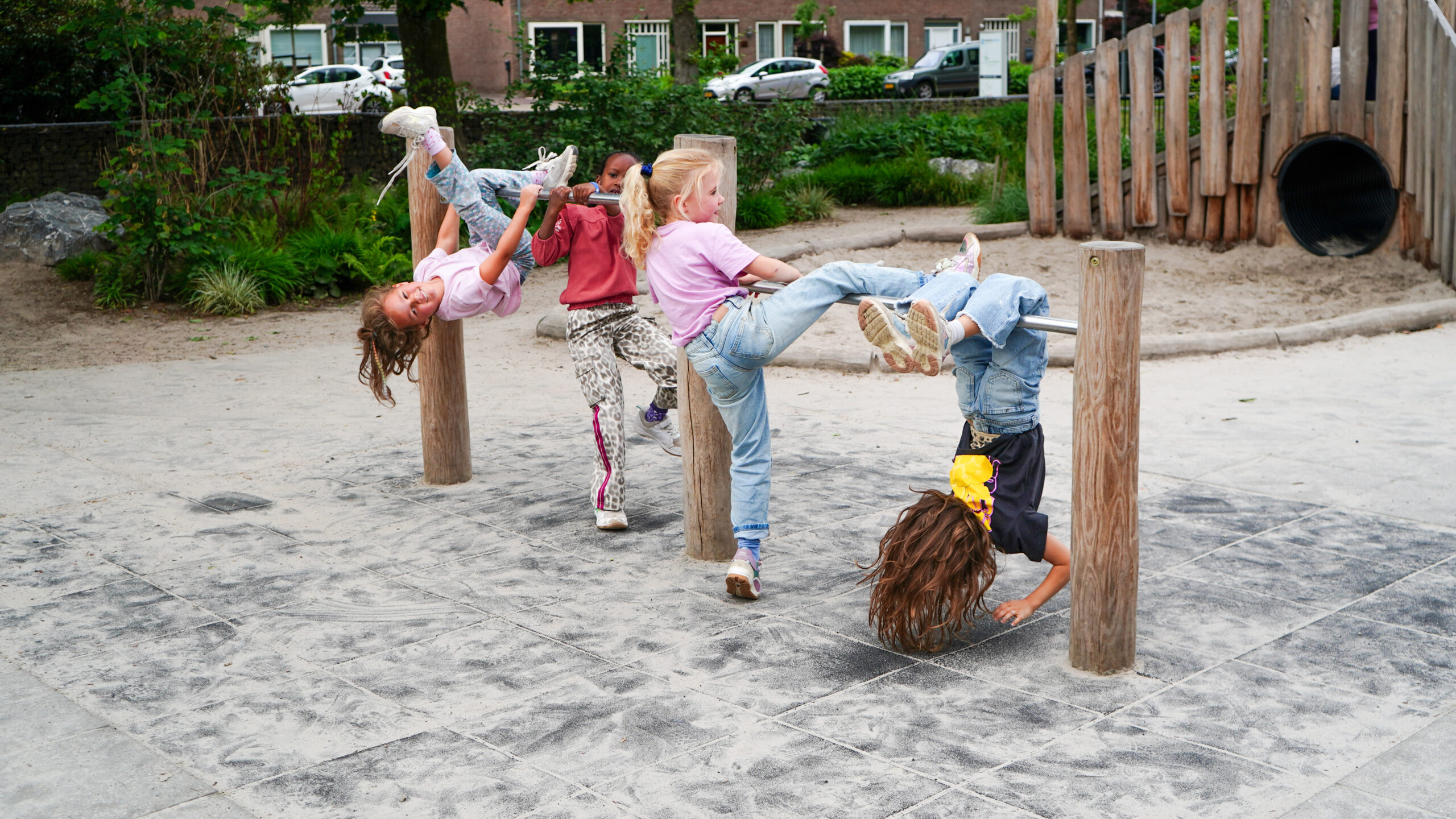 Aan de Bron Weert Kinderen spelen op een robina houten duoduikelrek op groenblauw schoolplein