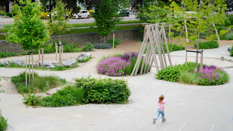 Overzicht van groenblauw schoolplein met robina houten speeltoestellen bij Basisschool Aan de Bron in weert