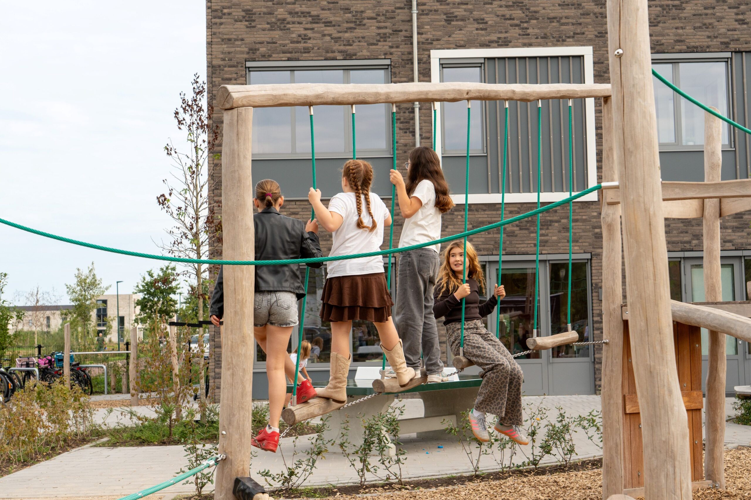 Basisschool Heilig Hart Dongen Kinderen spelen samen op robina houten speeltoestel van Sicuro op schoolplein van Basisschool Heilig Hart Dongen